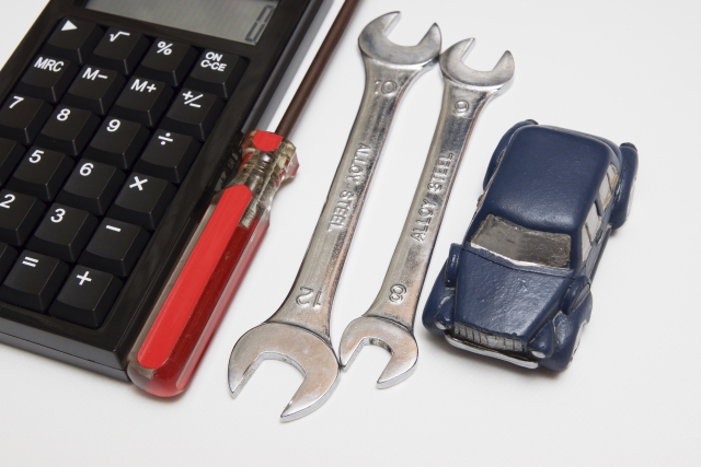 スパナやドライバーなどの整備工具とミニカーが並んだ、自動車整備をイメージした写真です。