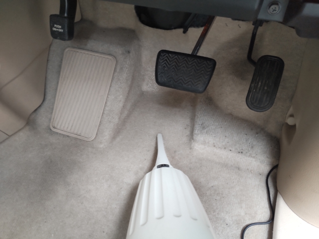 ハンディクリーナで運転席の下を掃除している