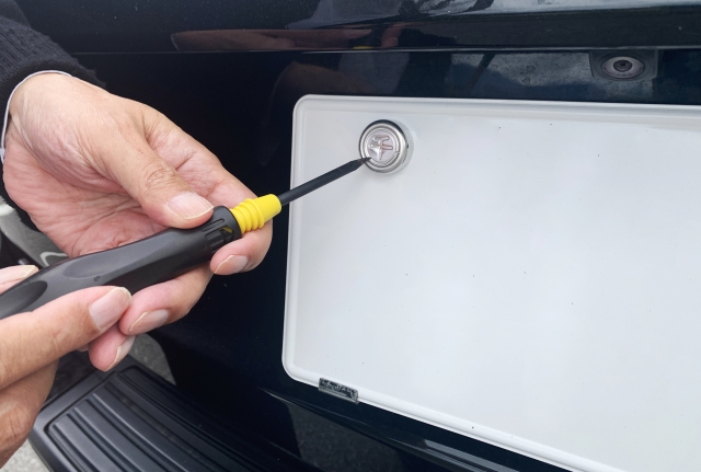 自動車のナンバープレートを取り付ける作業の様子