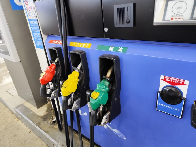 ガソリンスタンドの給油機に並んだ赤・黄・緑のノズル。レギュラー、ハイオク、軽油の3種類が設置されている。
