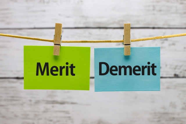 木の板に「Merit」と「Demerit」の札が吊るされているイメージ画像