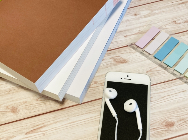 イヤホンとスマートフォンを使って音楽を楽しむイメージ。リラックスしながらお気に入りの曲を聴く様子を表しています。