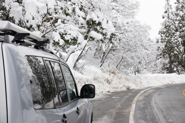 積雪した道路を走る車を撮影した写真で、シエンタの雪道走行や冬のドライブに関する記事用のイメージとして使用しています。