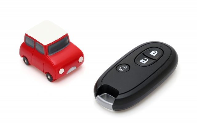 赤い車のミニチュアとスマートキーを並べたシンプルなイメージ写真です。